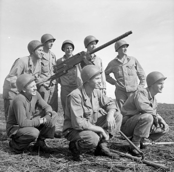A group of soldiers kneeling around a large gun